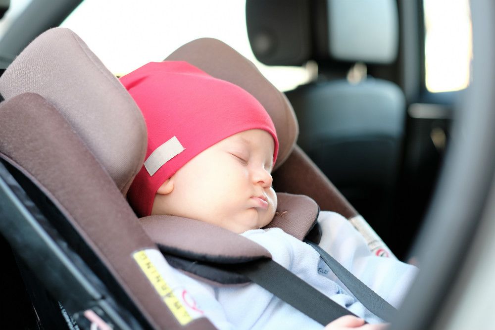 Infant car seat carrier with newborn baby properly secured with 5-point harness