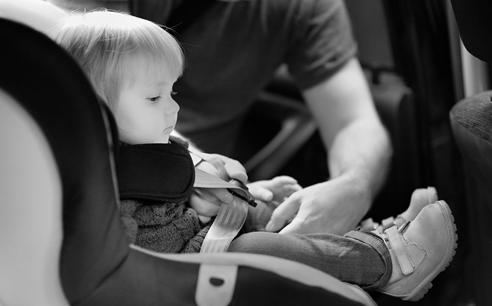 Car seat being installed showing LATCH connectors and seat belt routing