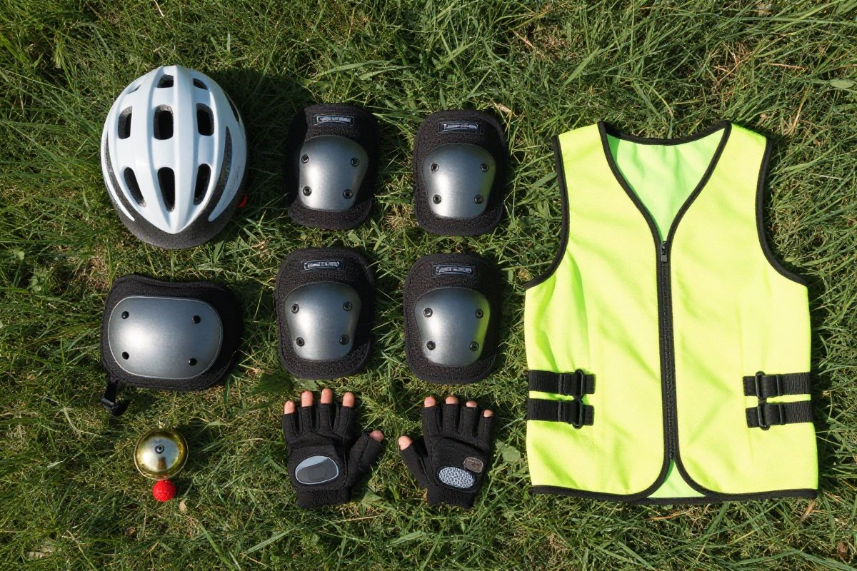 Children's cycling safety gear flat lay including helmet, pads, gloves, and reflective vest