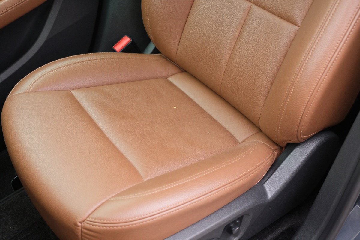 Vehicle leather seat showing compression dent and debris from prolonged car seat use