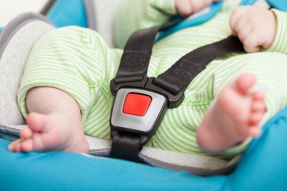 Demonstrating proper car seat harness tightness with pinch test