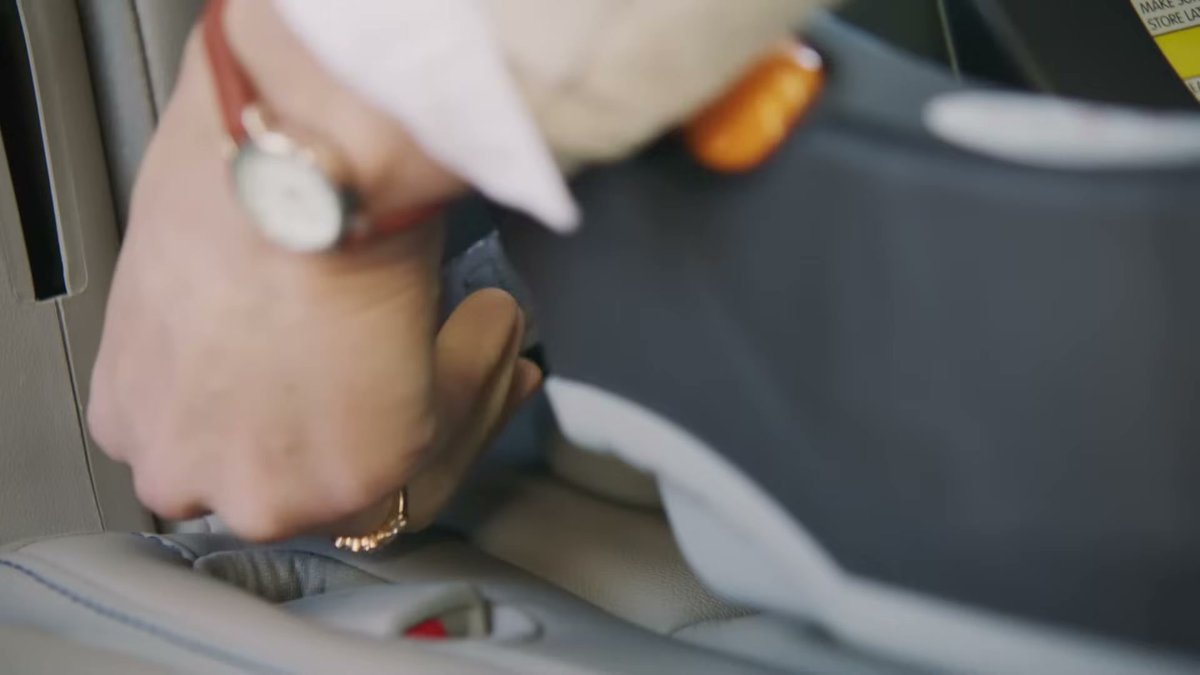 Close-up of hand securing Chicco KeyFit 30 car seat with LATCH system in vehicle