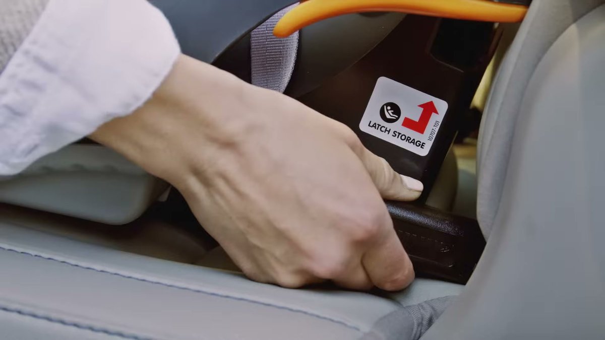 Hand securing LATCH storage on Chicco KeyFit 30 car seat base in vehicle